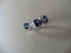18ct white gold trilogy ring set with 3 round cut sapphires weighing 0.70ct. These are surrounded in
