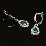 A pair of earrings with drip-shaped emeralds and brilliant cut diamonds