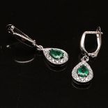 A pair of earrings with emeralds and brilliant cut diamonds