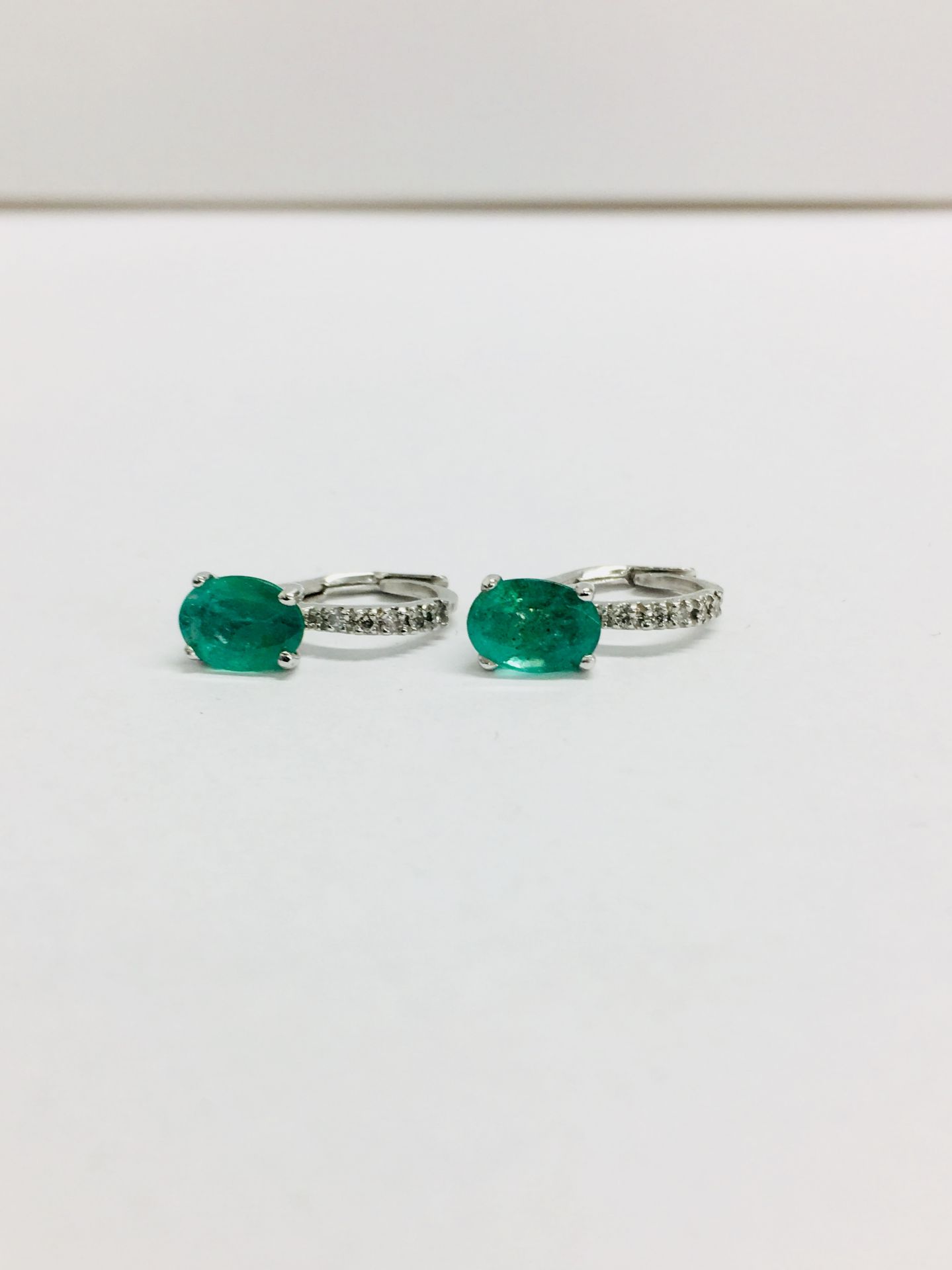 1.60ct emerald and diamond hoop style earrings. Each is set with a 7x 5mm oval cut emerald ( treated