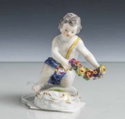 Figurine, Putto mit Blumengirlande, Meissen, blaue Schwertermarke, Porzellan, polychrom bemalt,