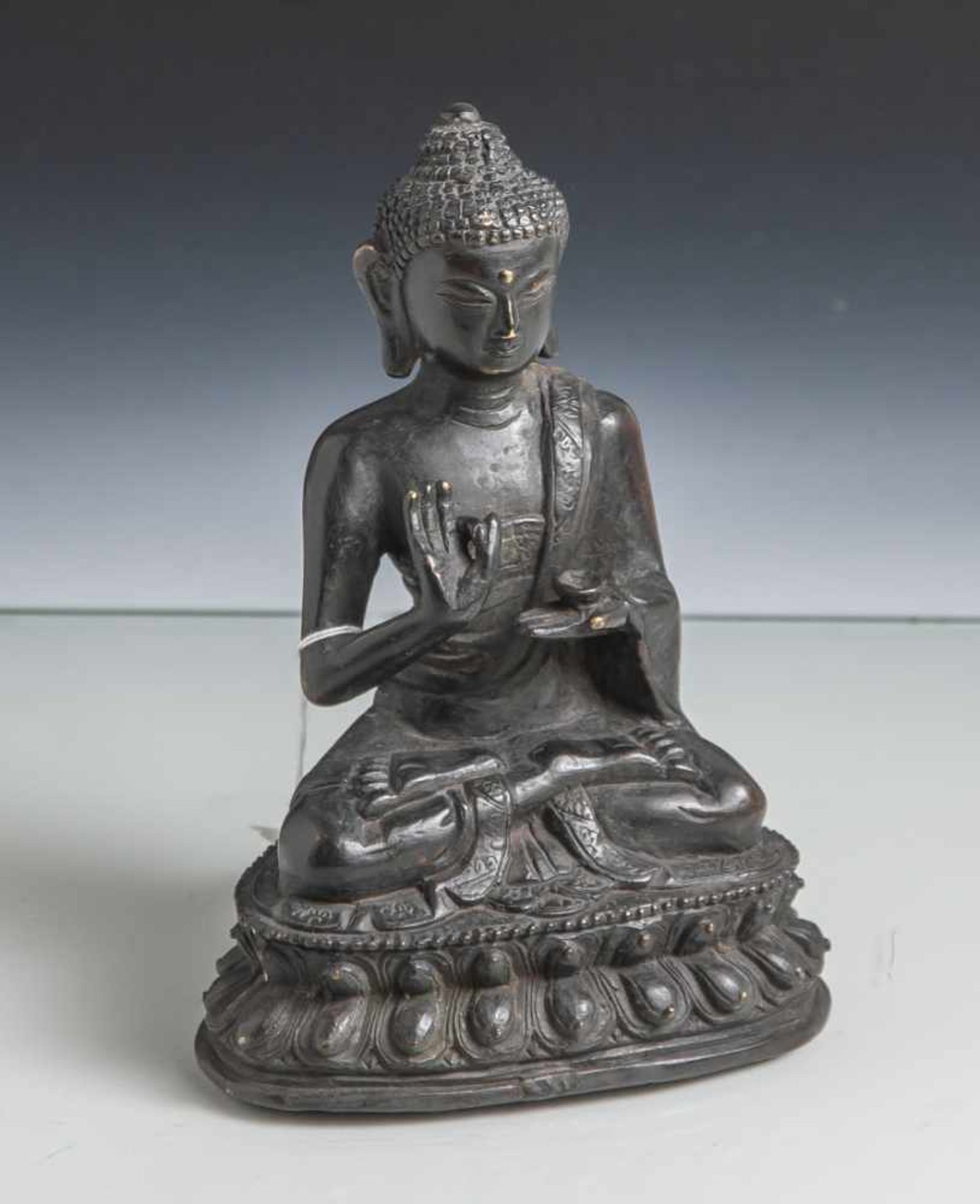 Bronzebuddha, wohl Indien 19. Jahrhundert, im Lotossitz, die Hände im Vitarka mudra. Auf