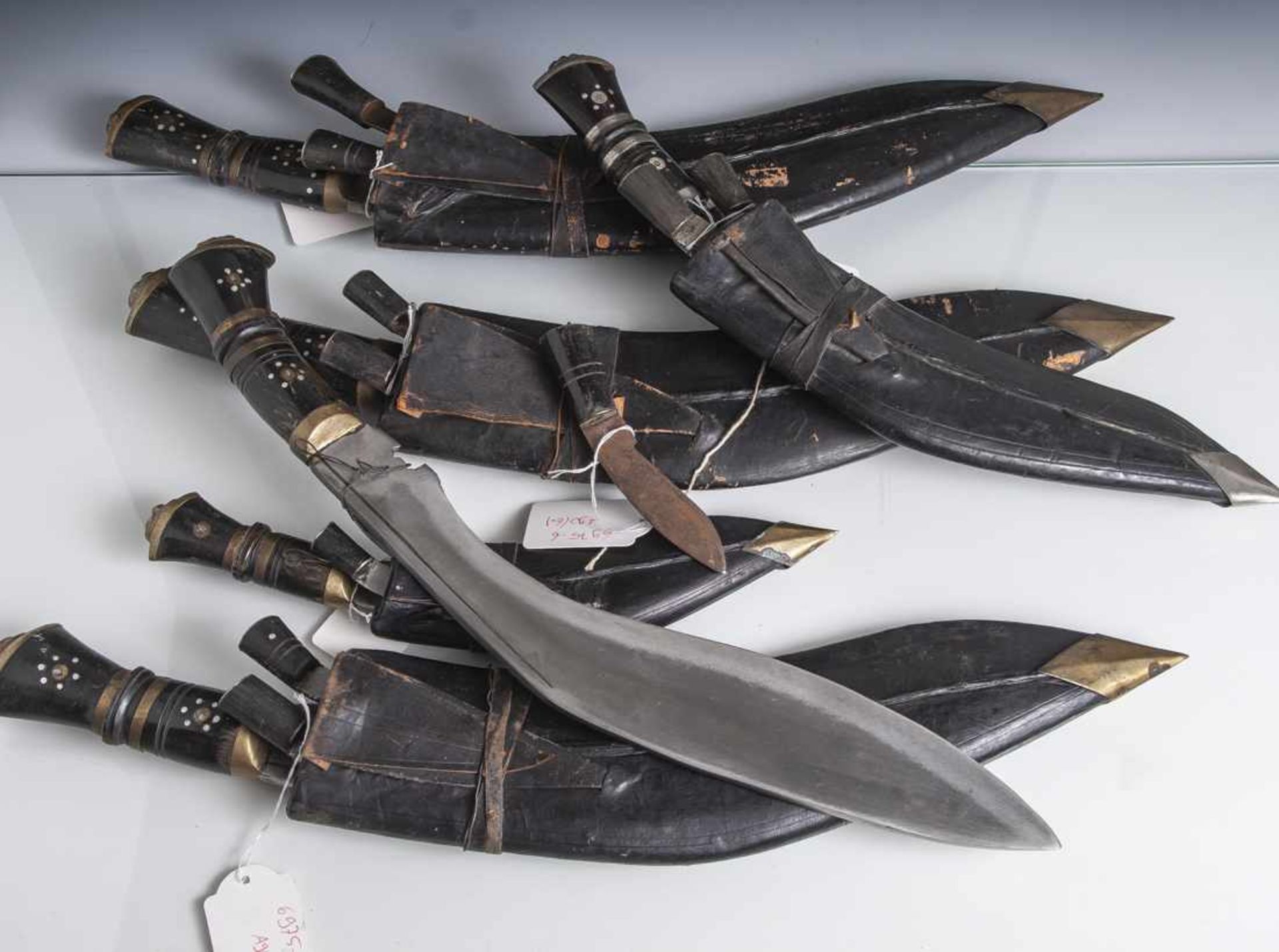 Konvolut von 6 versch. Gurkha Messern, Indien, jeweils mit kleinen Beimessern und Scheide aus Leder.