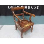 An Edwardian commode chair with cover, solid top rail over scroll arms.