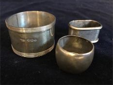 Three silver and white metal napkin rings