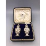 A boxed pair of silver cruets, makers mark ESB, hallmarked Birmingham 1914-15.