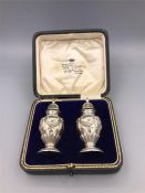 A boxed pair of silver cruets, makers mark ESB, hallmarked Birmingham 1914-15.