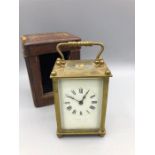 A brass carriage clock in a leather carry case