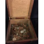 A large volume of collectable coins in a wooden box.