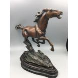 A galloping horse statue in copper alloy on a heavy base with indistinct signature