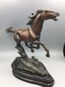 A galloping horse statue in copper alloy on a heavy base with indistinct signature