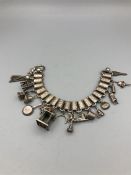 A white metal bracelet with a selection of charms, some hallmarked.