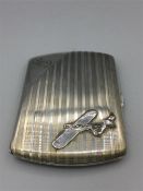 A silver cigarette holder with plane emblem.