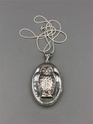 A silver locket with embossed owl on a silver chain