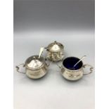 A hallmarked silver Walker and Hall cruet set to include mustards and salts, boue glass liners