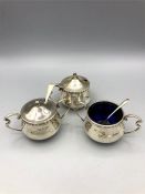 A hallmarked silver Walker and Hall cruet set to include mustards and salts, boue glass liners