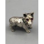 A heavy cast silver figure of a dog with ruby eyes.