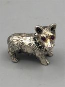 A heavy cast silver figure of a dog with ruby eyes.