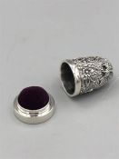 A silver thimble and pin cushion