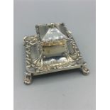 A silver square lidded inkstand, turned out feet to each corner, repousse scroll work around top and