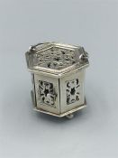 A silver miniature, hexagonal in shape, with carrying handle and opening door, pierced decoration