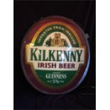 An illuminated Kilkenny beer sign with original swing bracket and taken out of box for photo.