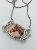A silver and enamel necklace depicting a horse on silver chain