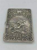 A Hallmarked silver wallet with a Stag Hunting scene, rubbed indistinct hallmarks.