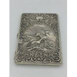 A Hallmarked silver wallet with a Stag Hunting scene, rubbed indistinct hallmarks.
