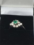 A white gold emerald and diamond cluster ring