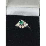 A white gold emerald and diamond cluster ring