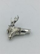 A silver whistle in the form of a stag.