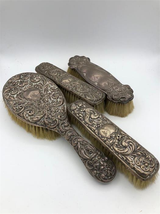 Four silver backed brushes.