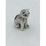 A silver cat pincushion with emerald eyes and ruby collar