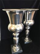 A pair of tall silver coloured thistle shaped vases