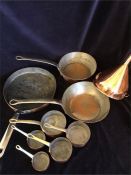 A large selection of copper items to include a set of graduated saucepans, funnel and frying pans.