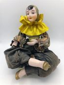 A Bisque Harlequin jester seated on a cushion