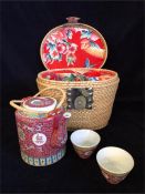 A wicker basket with Chinese teapot and two tea bowls