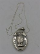 A Silver locket with embossed owl to the lid on silver chain