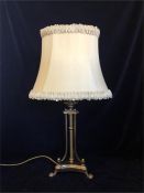 A brass table lamp on three feet