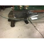 A glass coffee table with an elephant figure base