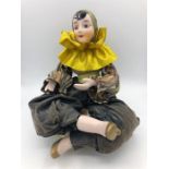 A Bisque Harlequin jester seated on a cushion
