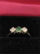 An 18ct yellow gold emerald and diamond three stone ring