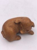 A wooden Japanese Netsuke in the form of a dog, signed to the base.