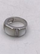 A silver ring set with CZ's and mother of pearl pannels