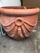 A pair of terracotta garden planters with sash style design.