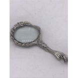 A silver hand held magnifying glass in the Art Nouveau style