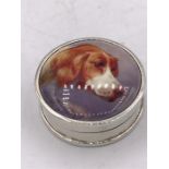A silver round pill box with enamel plaque depicting a dog