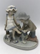 Lladro figure of children trying on shoes