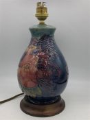 A Moorcroft lamp base with blue grounds, fruit and bird pattern